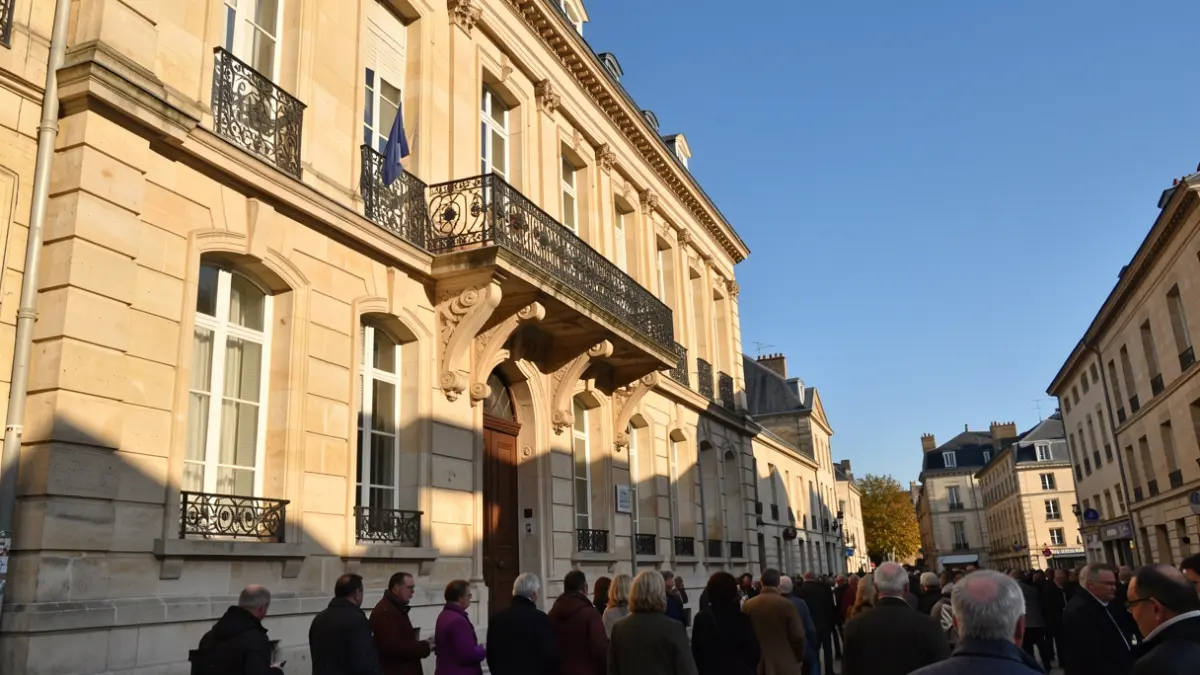 Generic image of a stone town hall facade with an ornate balcony and iron railings, under an afternoon sun.